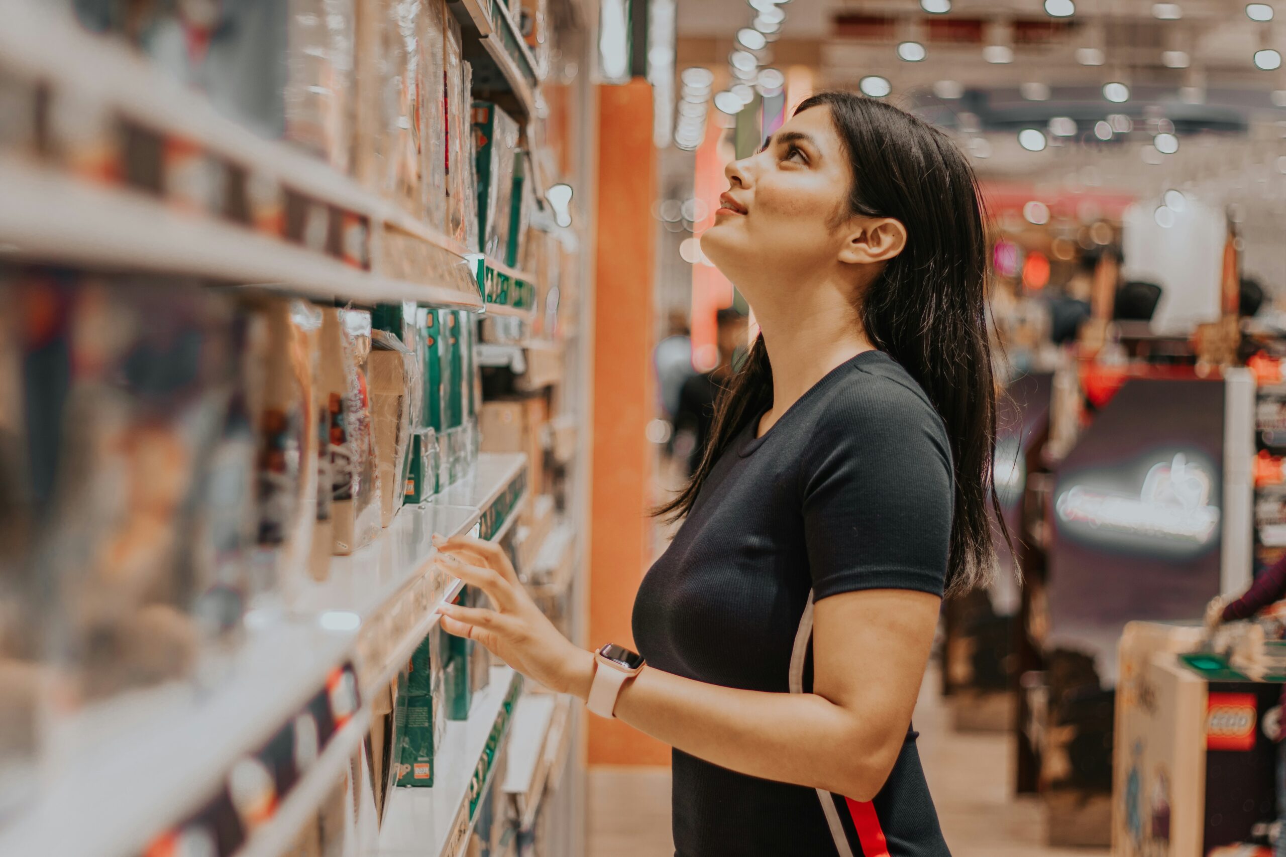 Woman browsing products and comparing prices while shopping in a modern retail store